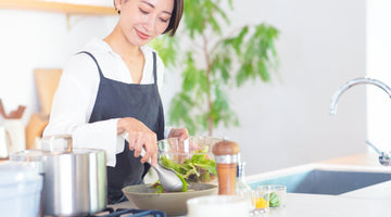 キッチンで鍋を使って調理する女性