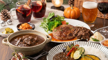 テーブルに並べたビーフシチュー、ハンバーグ、ソーセージ、カレーとホットワイン
