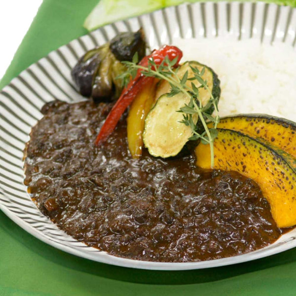 牛たん黒カレーの皿に盛り付けられた黒いカレーと白ご飯、色とりどりの野菜がトッピングされた美しいプレート