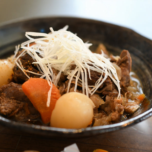 牛たんブロック1本を使用した煮込み料理の画像。柔らかい牛たんと大根、にんじん、玉ねぎが入っており、白髪ねぎがトッピングされた美味しそうな一品。