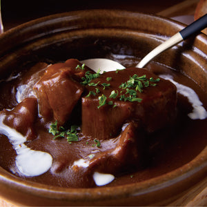 贅沢な牛たんシチュー、濃厚なブラウンソースに牛たんとハーブがトッピングされた美味しそうな料理の皿