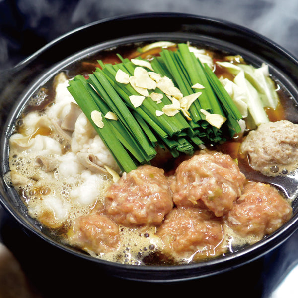 牛たん生つくねが入った鍋料理の画像。つくね、ネギ、キャベツ、スープが見え、温かい料理のスタイルを表現。
