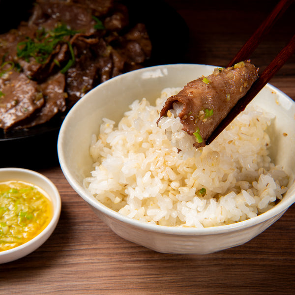 薄切り牛たん焼肉用を箸で持ち上げている様子と白ご飯の盛り付け、背景に焼肉が見えるシーン